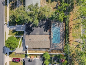 An aerial view of a residential area with a swimming pool, a garage, and a driveway.