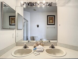 Bathroom features two sinks and a toilet, with a large mirror above.