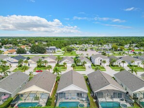 Stylish homes with attached garages and a shared pool area, surrounded by well-manicured lawns and palm trees.