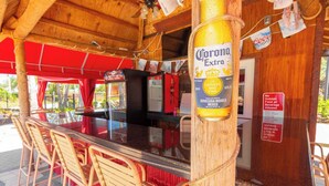A bar area with a Corona Extra beer bottle, red chairs, and a sign prohibiting outside food or beverages. - Lesa's Solana Resort Vacation Home (Davenport)