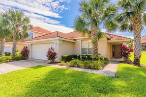 A residential house with a red-tiled roof, a garage, and a well-maintained lawn with palm trees. - Lesa's Solana Resort Vacation Home (Davenport)