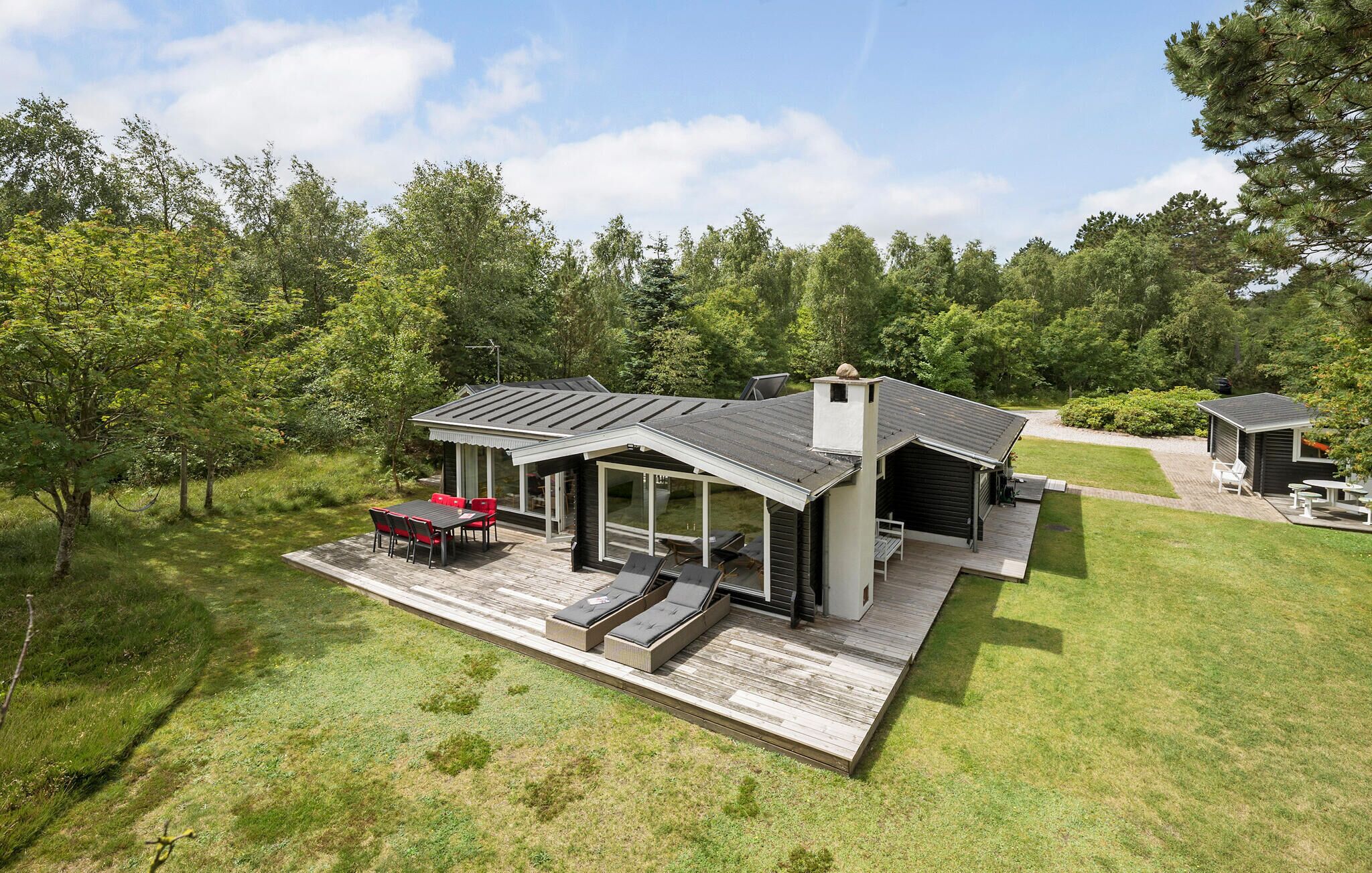 A modern house with a deck, a covered patio, and a small shed.