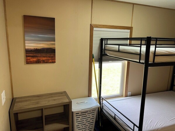 A bunk bed room with a window, a desk, and a painting on the wall.