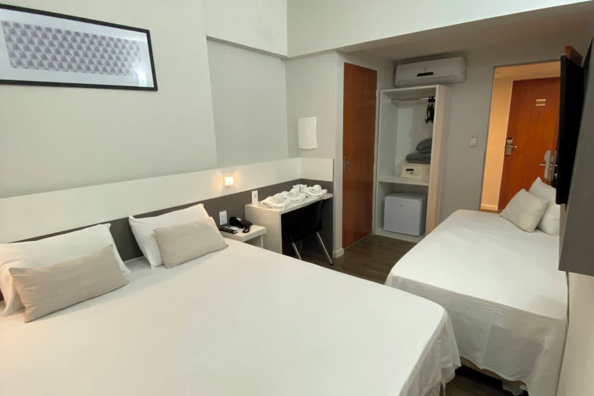 Habitació d'hotel amb dos llits, un escriptori, una cadira, un armari i un bany.