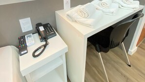 Une chambre d’hôtel équipée d’un bureau, d’un téléphone, d’une prise électrique et d’une chaise.