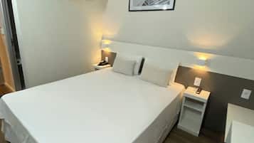 Une chambre d’hôtel avec un grand lit, des tables de chevet avec des lampes, un climatiseur fixé au mur et un tableau encadré accroché au mur.
