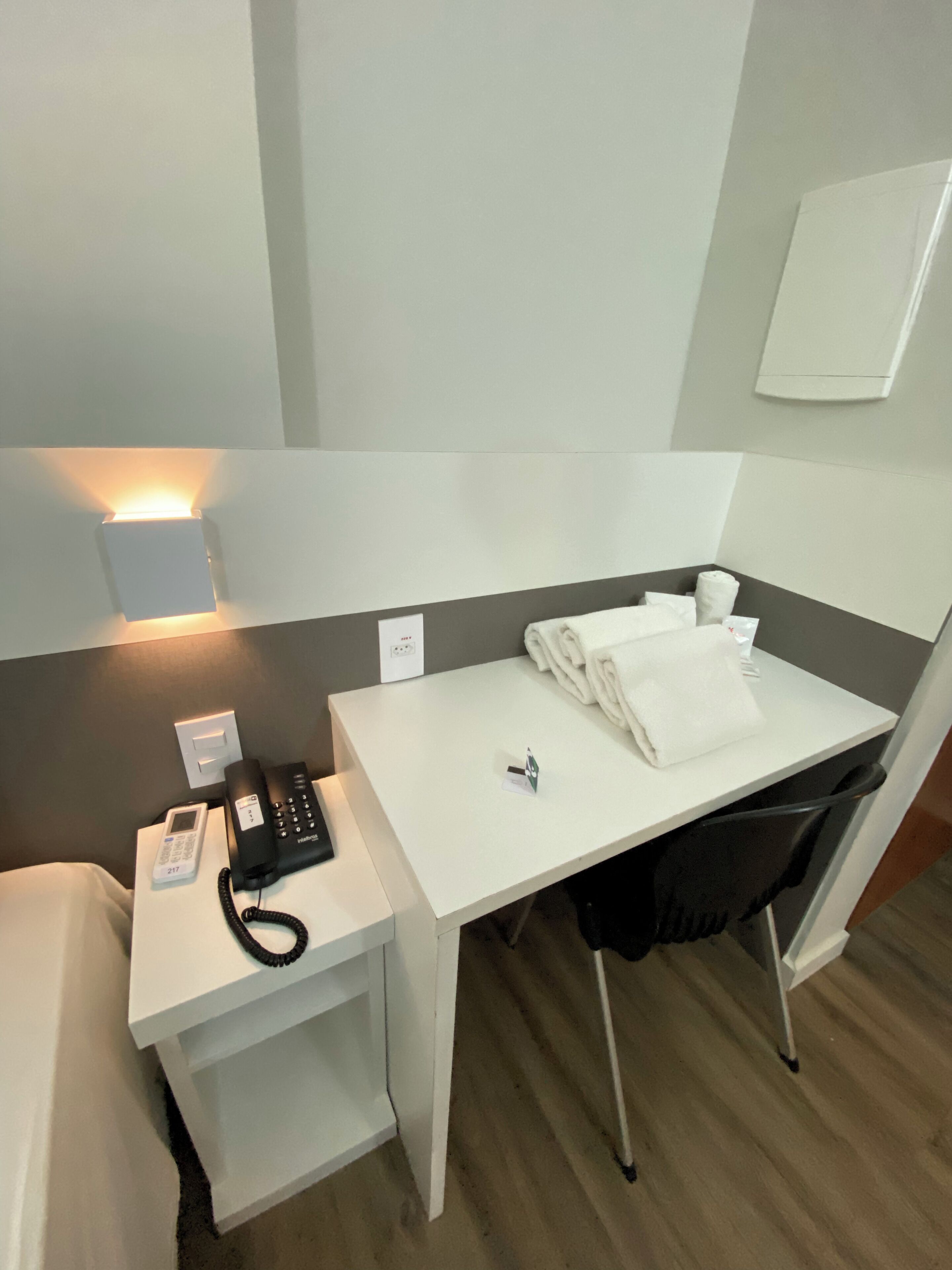 Une chambre d’hôtel équipée d’un bureau, d’un téléphone, d’une chaise et d’une serviette soigneusement pliée posée sur le bureau.