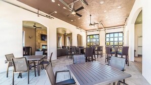 A spacious indoor dining area with multiple tables and chairs, large windows, and a high ceiling with exposed beams. - Game Room - Private Pool - Windsor at Westside (Kissimmee)