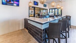 A bar area with a marble countertop, dark tiled backsplash, wicker bar stools, and pendant lighting. - Game Room - Private Pool - Windsor at Westside (Kissimmee)