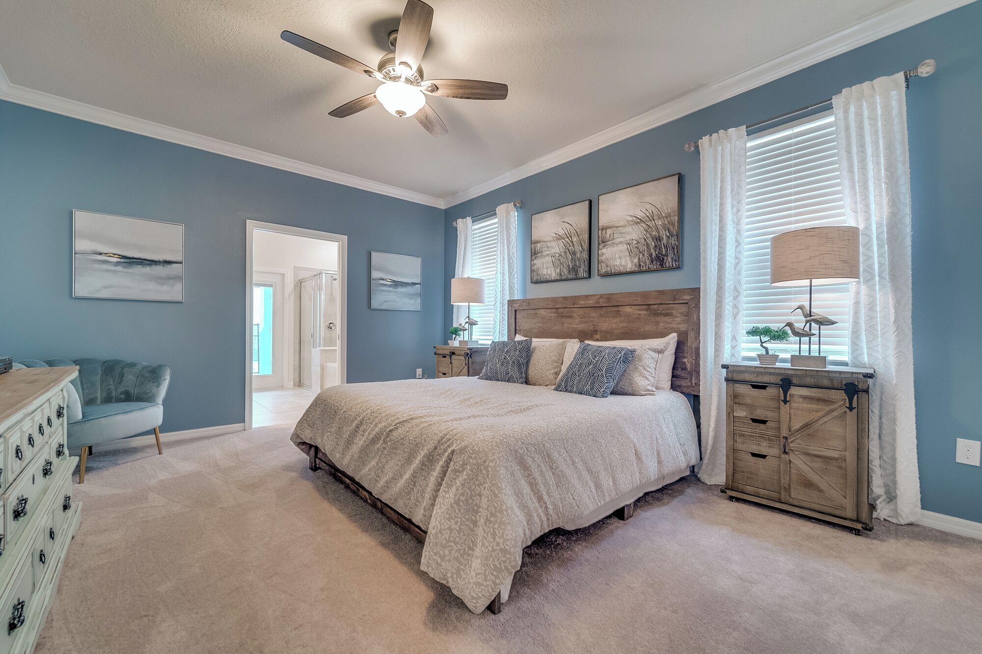 A bedroom with a bed, a dresser, a chair, and a ceiling fan.