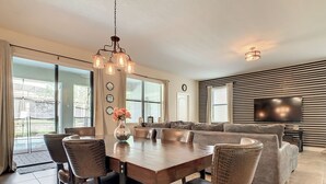 A dining area with a wooden table and chairs, a vase with flowers, and a chandelier.