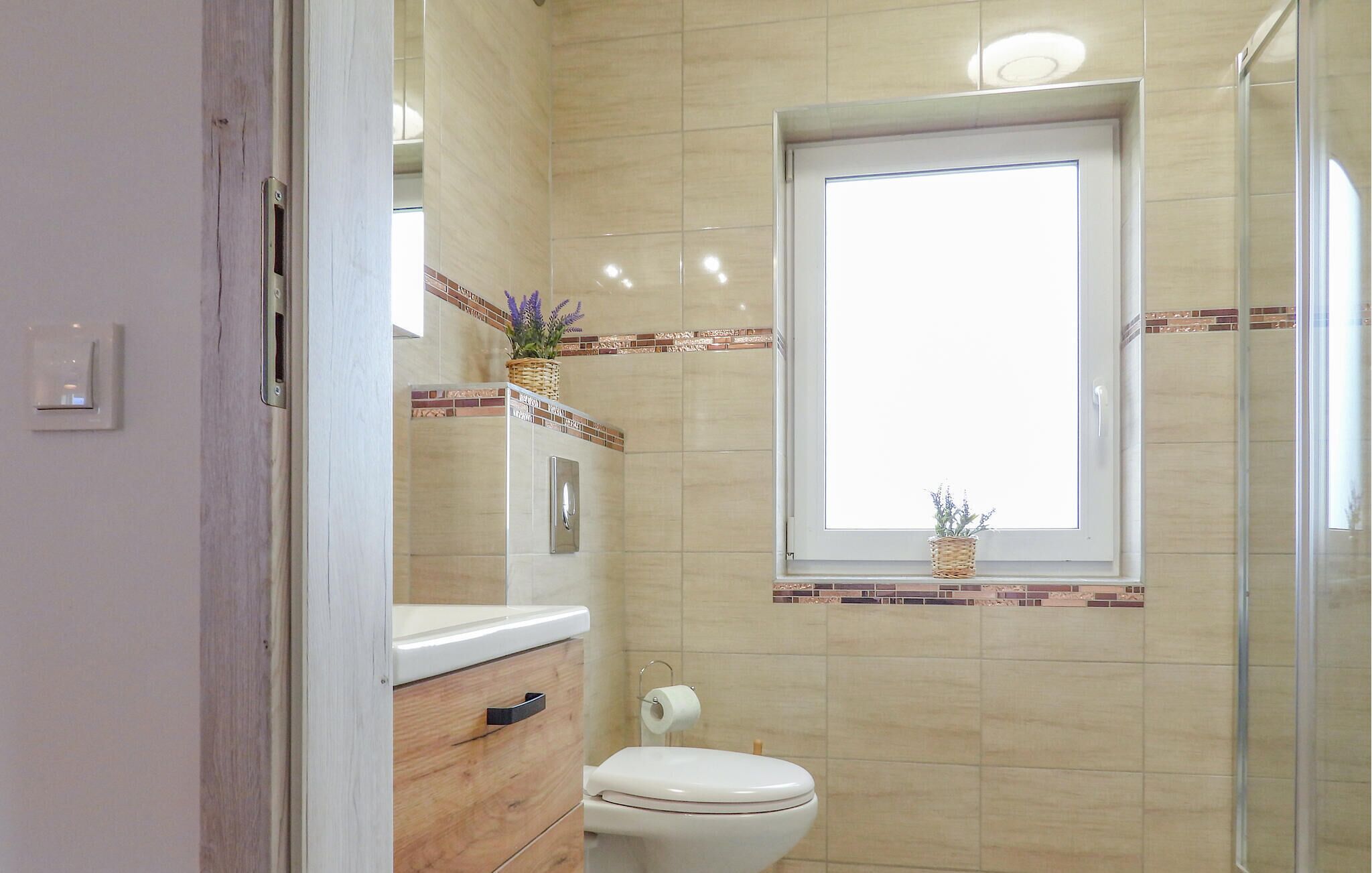 Un baño con inodoro, espejo, ventana y zona de ducha.