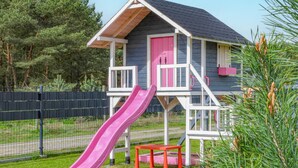 Ein Spielhaus für Kinder mit einer rosa Rutsche, einem roten Tisch und einer rosafarbenen Tür.
