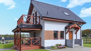 Ein zweistöckiges Haus mit Balkon, Schornstein und einem Blumenbeet.