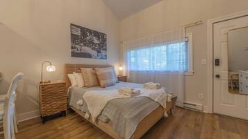 A bedroom with a bed, bedside tables, a lamp, a window with curtains, a mirror, and a wall-mounted picture.