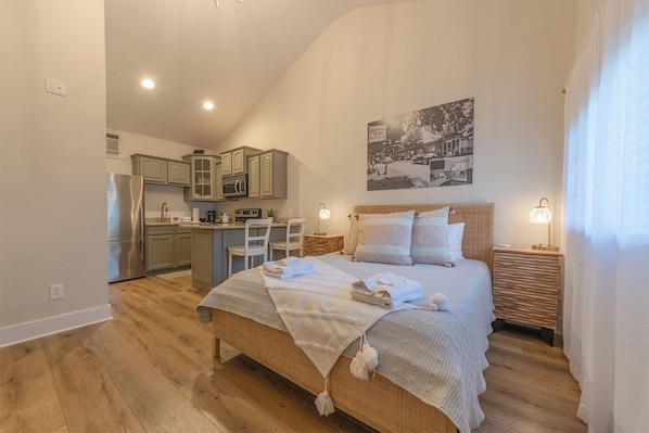 Une chambre à coucher avec un grand lit, une table de chevet, une lampe et un tableau accroché au mur.