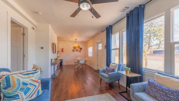A spacious living room with a ceiling fan, a dining area with a table and chairs, and large windows with curtains. - Discover comfort at Pine Cove, a cozy 1-bedroom retreat in scenic Douglas, MI. (Douglas)