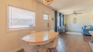 A dining area with a round table and chairs, a ceiling fan, and a living room with a sofa and a window with blinds. - Discover comfort at Pine Cove, a cozy 1-bedroom retreat in scenic Douglas, MI. (Douglas)