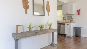 A kitchen with white cabinets, a wooden countertop, a dishwasher, and a trash can. - Discover comfort at Pine Cove, a cozy 1-bedroom retreat in scenic Douglas, MI. (Douglas)