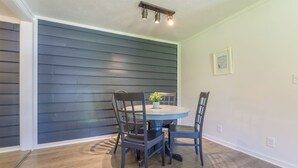 A dining area with a round table and four chairs, a potted plant on the table, and a ceiling light fixture above. - Hickory Cottage: Cozy 2-Bedroom in Douglas, MI, close to beaches, downtown, antiques and more!* (Douglas)