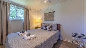 A neatly made bed with a quilted cover, a bedside lamp, and a world map on the wall. - Hickory Cottage: Cozy 2-Bedroom in Douglas, MI, close to beaches, downtown, antiques and more!* (Douglas)