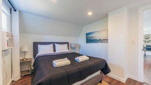 Una habitación de hotel moderna con una cama grande, una mesita de noche, una lámpara y un cuadro en la pared.