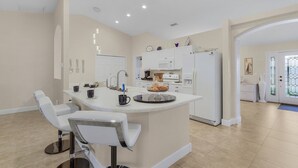 A modern kitchen with white cabinetry, a central island with seating, and a breakfast bar.