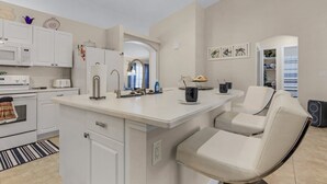 A modern kitchen with white cabinets, a built-in microwave, and a central island with seating.