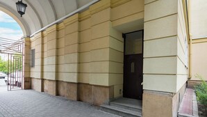 Una entrada de edificio con suelo de baldosas, una reja metálica y una puerta oscura.