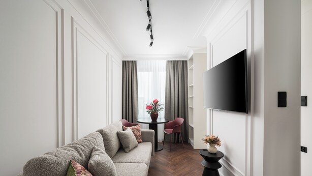 Una sala de estar moderna con un sofá, una mesa de comedor y un televisor de pantalla plana montado en la pared.