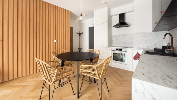 Una cocina moderna con armarios blancos, encimera de mármol y campana extractora negra.