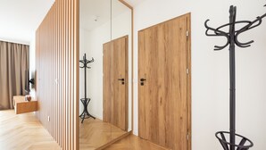 Una habitación moderna con suelo de madera, un perchero y un armario con espejo.