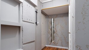A hallway with white walls, a wooden floor, and a door leading to a room with a white door and a wall with gold speckles.