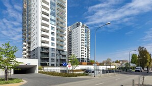 A modern high-rise building with multiple balconies and a pedestrian entrance.