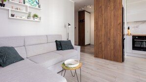 A modern living room with a grey sofa, a small round table with a bowl, and a wooden partition.