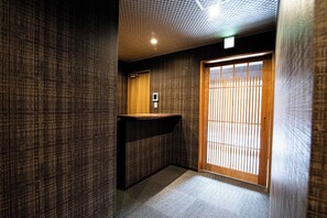 Compact bathroom with a minimalist design, featuring a textured wallpaper, carpeted floor, and a traditional lattice door.