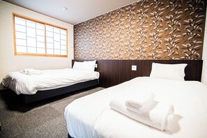Ein Hotelzimmer mit zwei Betten, einem großen Fenster und einer Wand mit Muster.