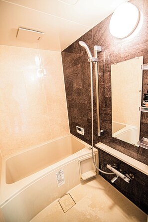 Ein modernes Badezimmer mit Badewanne, Dusche, Waschtisch und Spiegel sowie Toilette.
