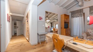 Un'ampia zona giorno con tavolo da pranzo in legno, divano e cucina sullo sfondo.