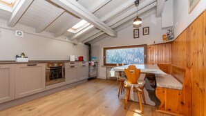 Una cucina con armadietti in legno, un tavolo da pranzo con panche, una finestra con vista e un lucernario.