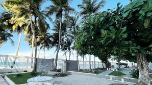 A patio area with a mosaic-tiled table and benches, surrounded by palm trees and a view of the ocean.