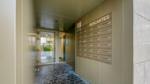 Un pasillo con un buzón de correo identificado con el nombre DESCARTES y una puerta de cristal que da a un espacio exterior.