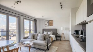 Una habitación de hotel moderna con cama, sofá, mesa de comedor y kitchenette.