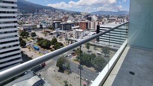 Un edificio alto con vistas a un paisaje urbano, que incluye varios edificios y una cadena montañosa distante.