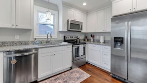 A modern kitchen with white cabinets, stainless steel appliances, and a granite countertop. - 4BR Norfolk Home • Game Room • Dog Friendly (Norfolk)