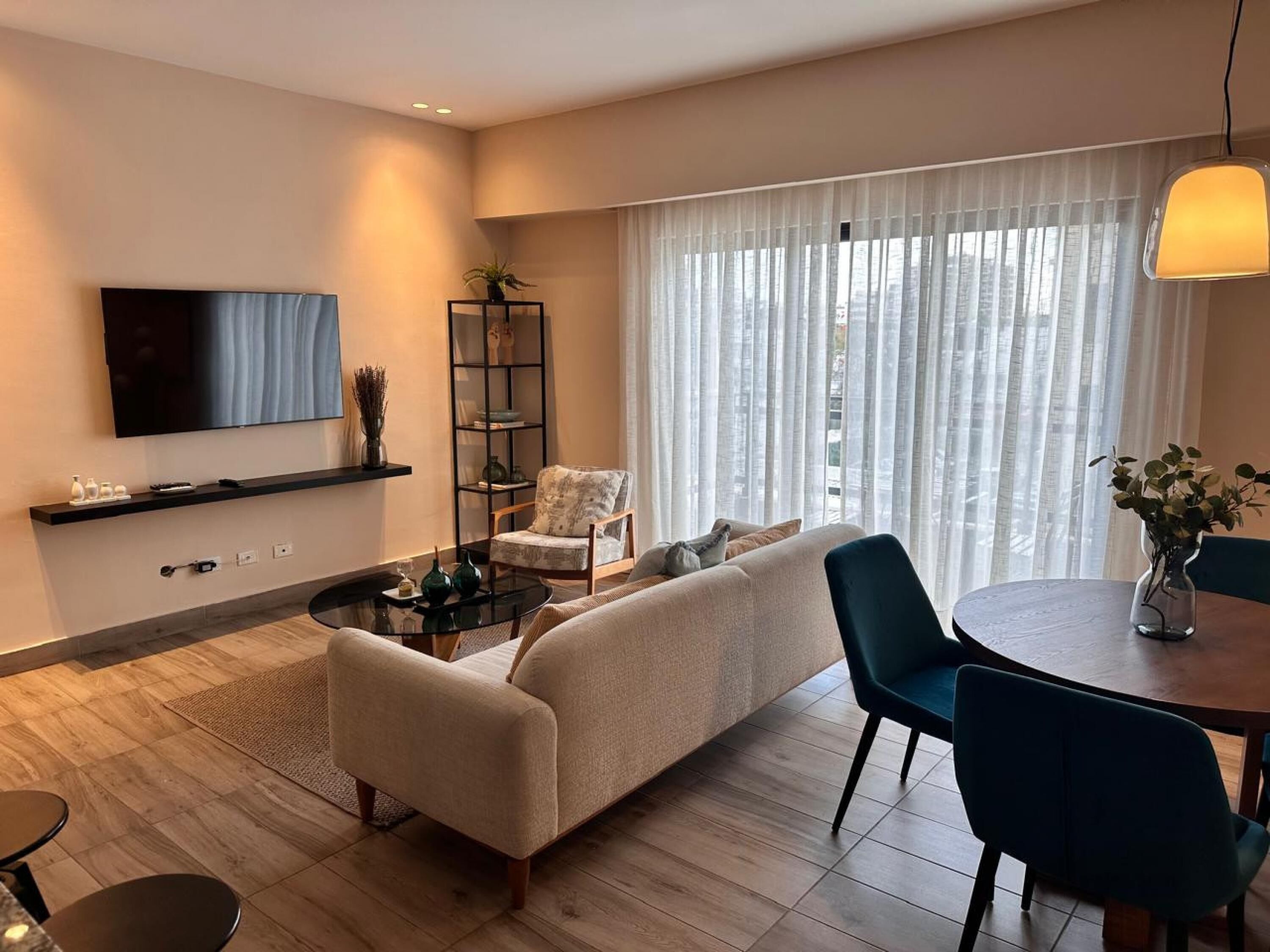 A modern living room with a sofa, a coffee table, a TV, and a dining area with chairs and a table.