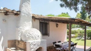Um pátio com forno de tijolos, área de estar externa e pérgola.