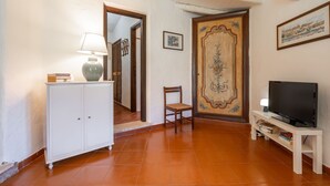A living room with a white cabinet, a wooden chair, a TV on a stand, and a door with a decorative panel.