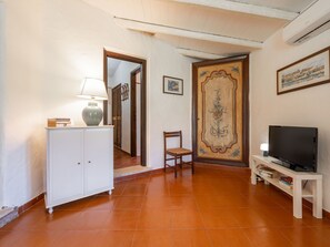 A living room with a white cabinet, a wooden chair, a TV on a stand, and a door with a decorative panel.