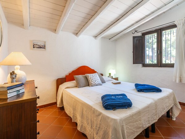 A bedroom with a bed, a nightstand, a lamp, and a window with curtains.